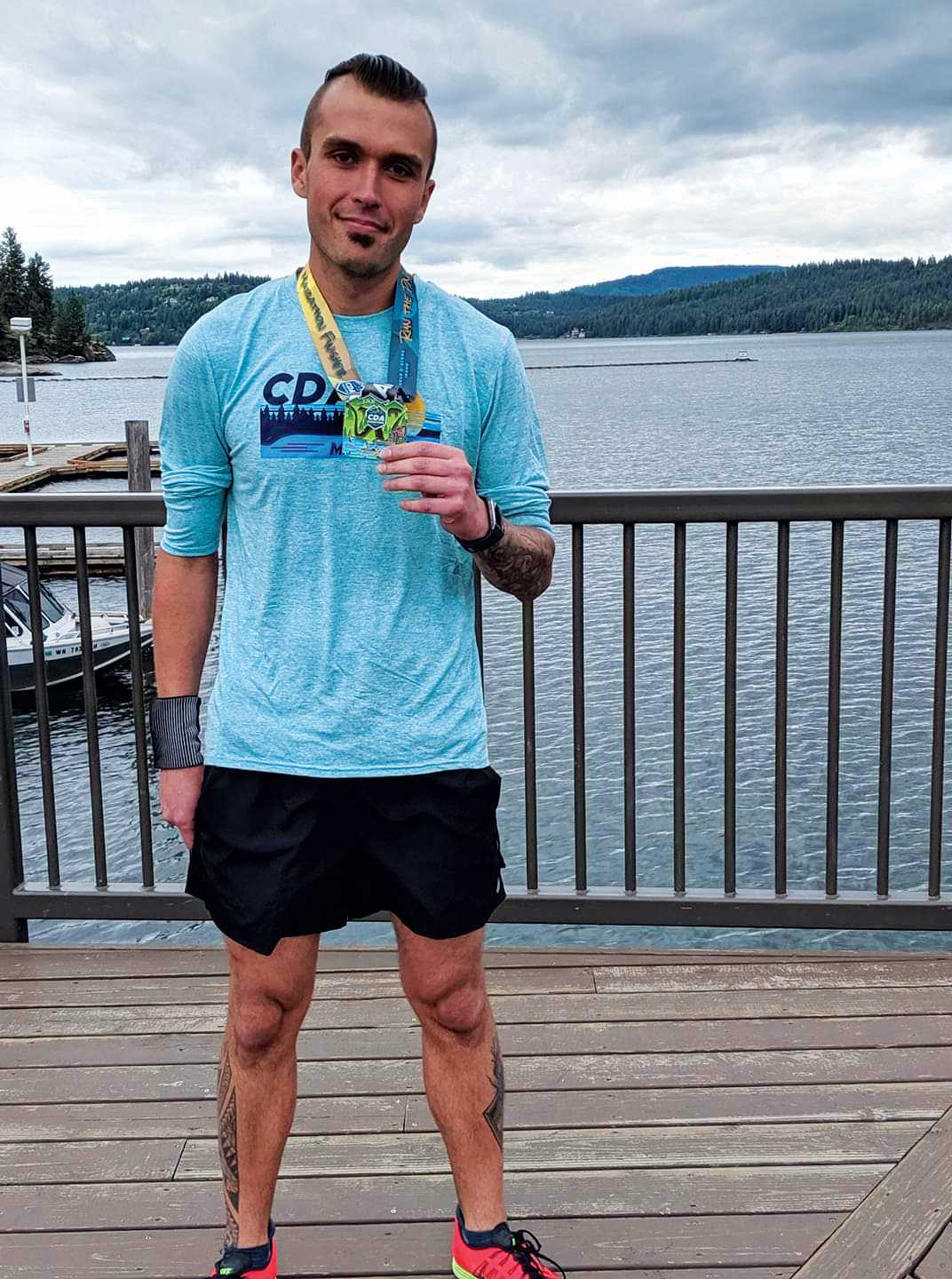 Person holding marathon medal with a lake in the background.