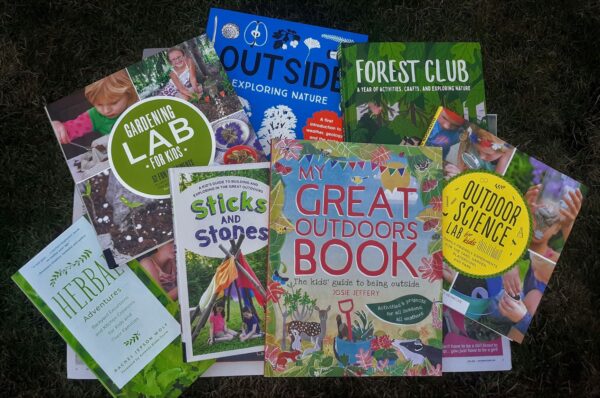 Various nature books for kids, that provide activities and ideas for learning about science, nature, art, and more -- displayed on the grass with their covers showing.