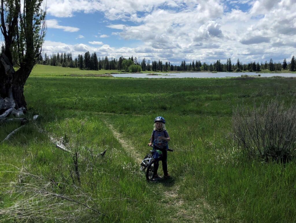 A kid biking along a lake trail.