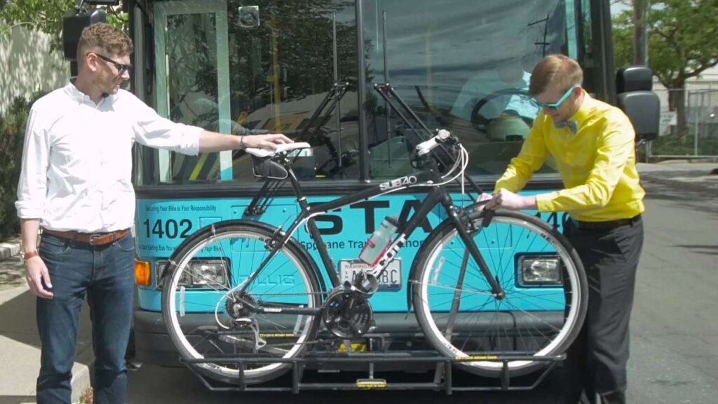 Two guys loading a bike onto a bike rack on a STA bus.