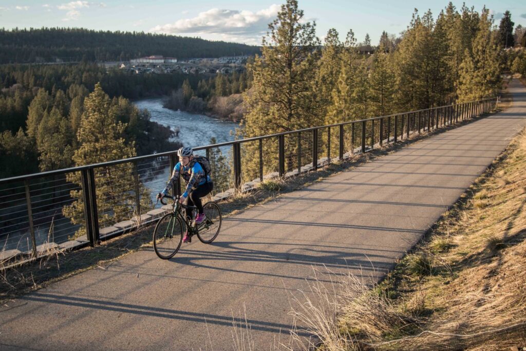Person biking on the Centennial Trail that runs alongside the Spokane River.