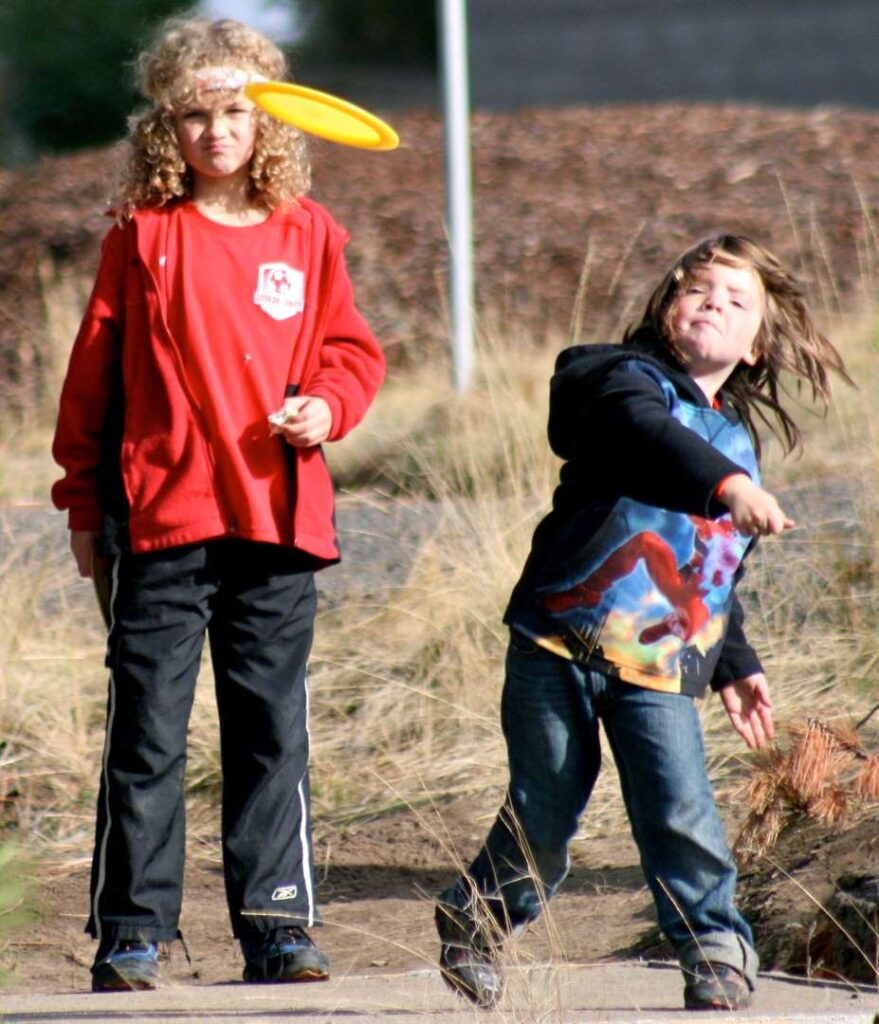 Two kids playing disc golf.