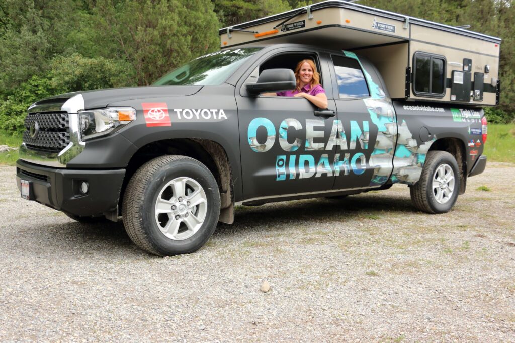 A woman smiling while driving a truck camper.