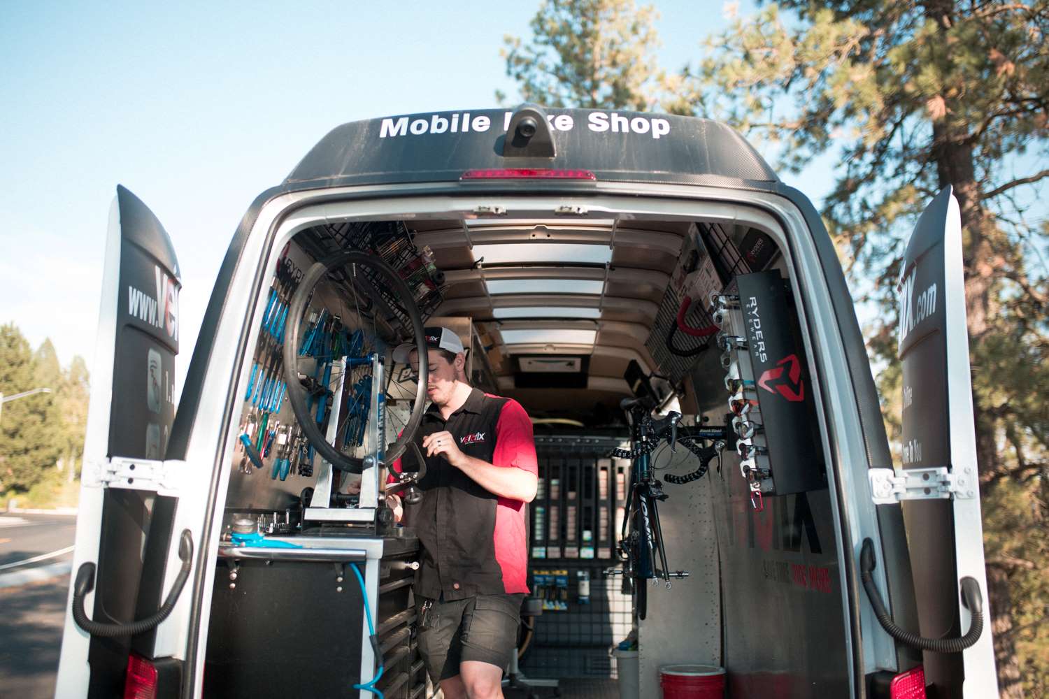 A man fixing a bike in a mobile van bike repair shop.