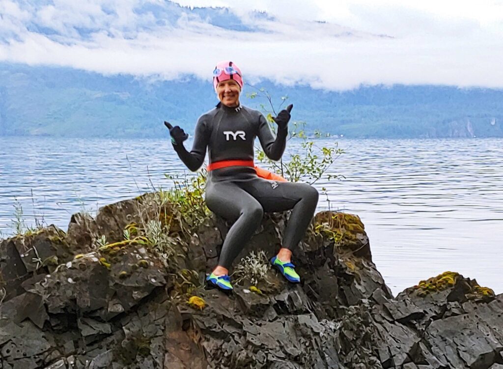 A woman smiling with a wet-suit on.