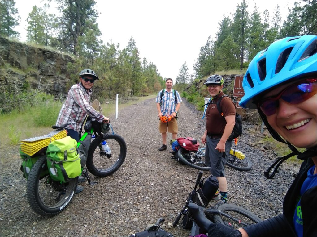 A woman taking a selfie with three other men bike riders.