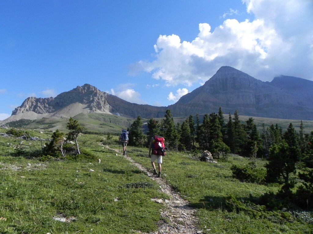 Backpackers hike beneath Gable Mountain in Glacier National Park, near the eastern terminus of the Pacific Northwest Trail.