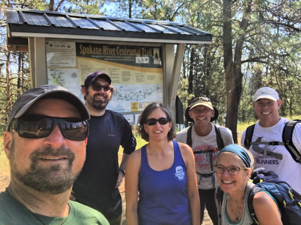A group of friends posting in front of a trail map.