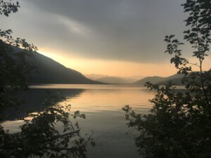 A lake reflecting the sunset with mountains in the background.