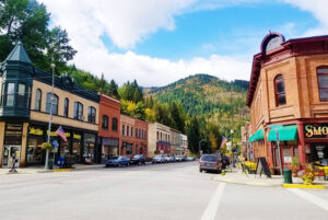 Old buildings on main street with a forested mountain in the background.