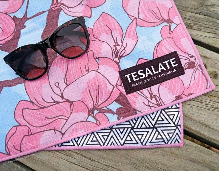 A cherry blossom beach towel with sunglasses on top of it.