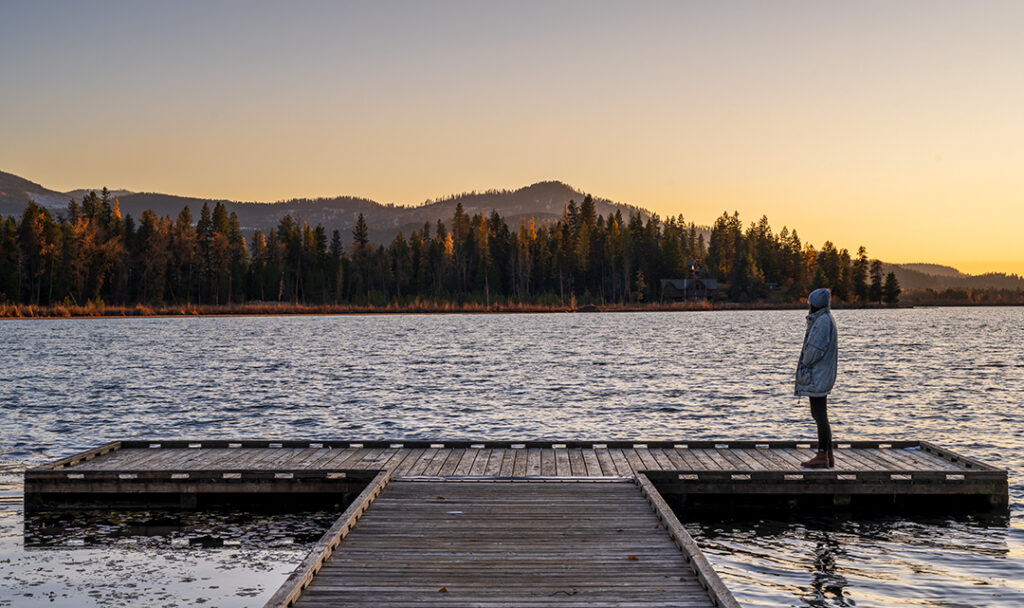 A person on a dock overlooking a lake.