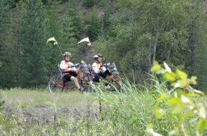 A couple tricycling down a trail.