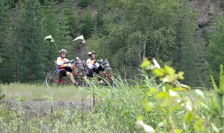 A couple tricycling down a trail.