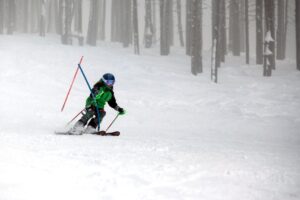 Ski racer turning around a slalom gate on race course.