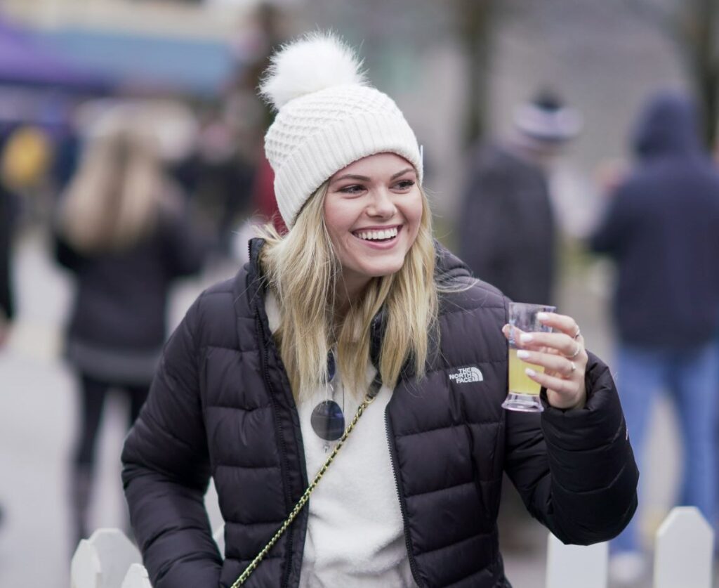Woman wearing winter pom-hat and holding a glass of beer at Winterfest in Chelan, Washington.