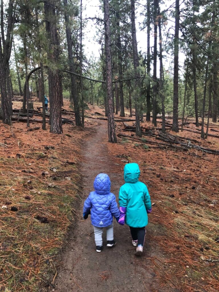 Two little girls walking together, holding hands, along a trail in Dishman Hills Natural Area.