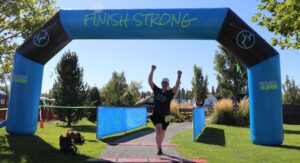 Person with raised hands while crossing finish line.