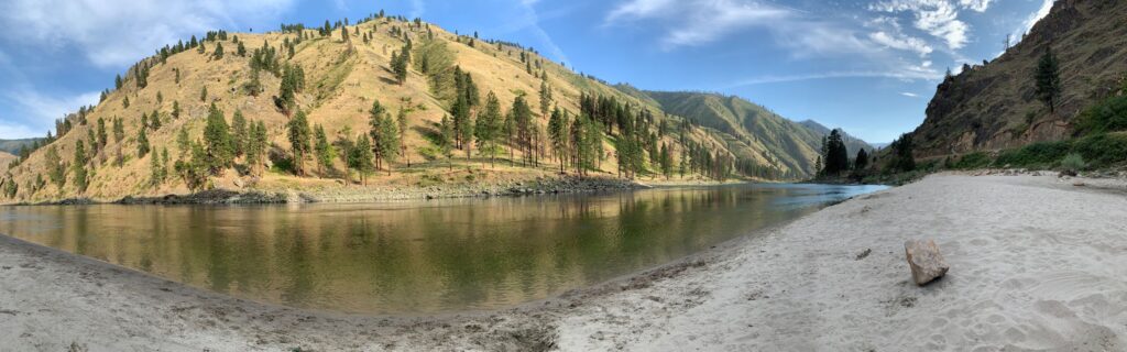 Sandy beach along the Snake River in Idaho. Rugged, hilly, arid landscape, and flat water of a river eddy.