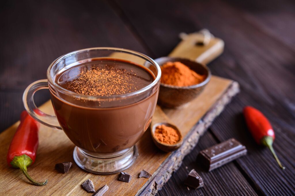 Mug of spicy hot chocolate, with chili peppers and grated chocolate.