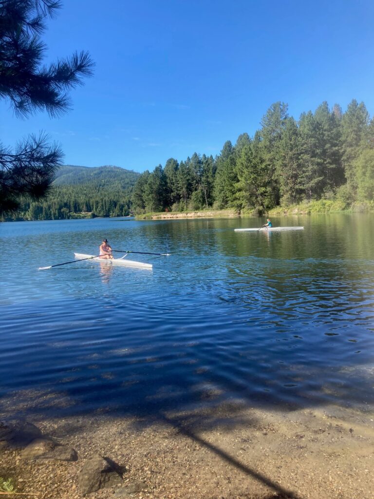 Woman kayaking towards the sandy beach at Priest River Recreation Area. Blue sky and sunshine.