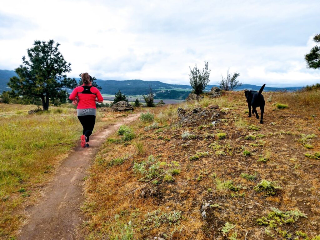 Runner with her dog along a trail at Antoine Peak.