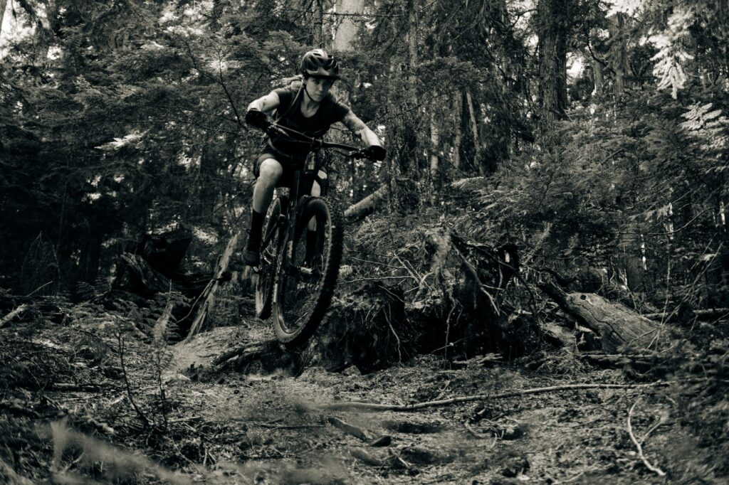 Woman mountain biking on a rugged, forested dirt trail in the Yaak wilderness of northwest Montana.