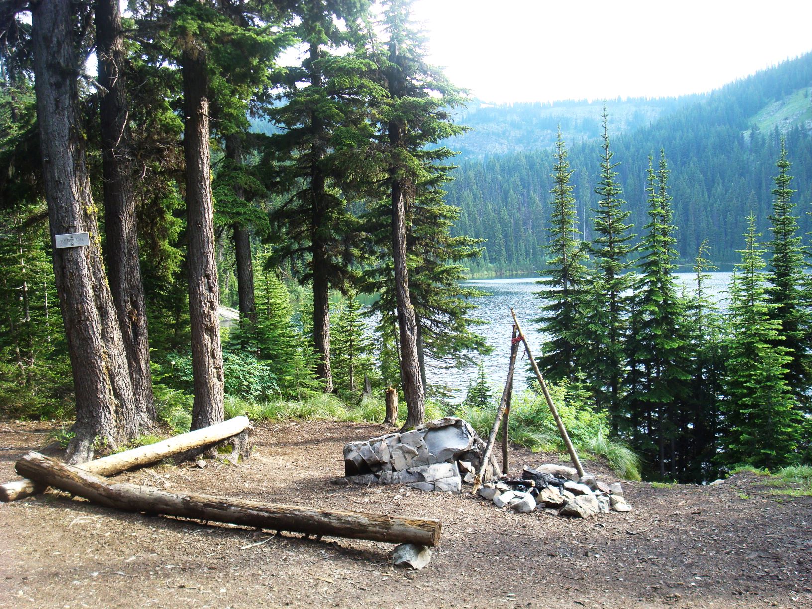 Blossom Lake campsite with rock campfire ring with view of lake and trees.