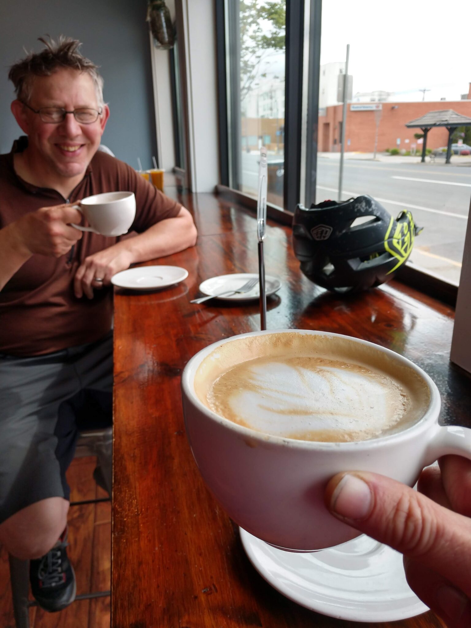 Two people drinking espresso from mugs inside a coffee shop.