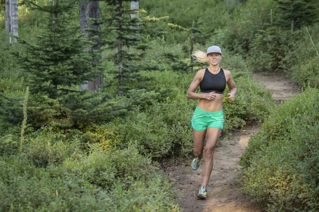 Woman trail runner cruising along a forested singletrack trail at Mt. Spokane State Park.