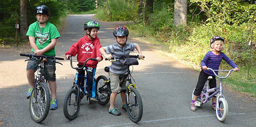 Three boys and girl on their bikes ready to ride the campground loop road.