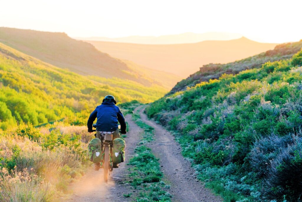 Bikepack riding a gravel road on Oregon's Big Country Route, alongside sagebrush.