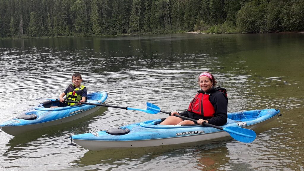 Mom and young son sitting in their blue kayaks on Priest Lake.