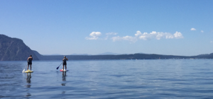 Two people stand-up paddling on the flat water of Lake Pend Oreille.
