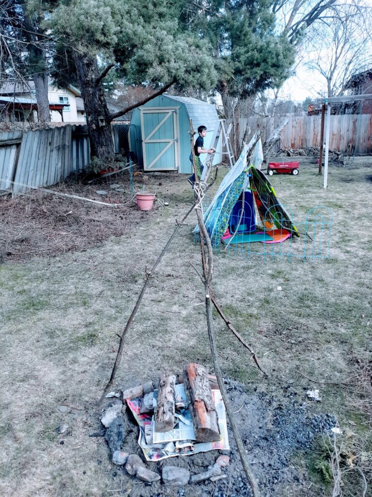 A child in a backyard practicing shelter and fire making skills.