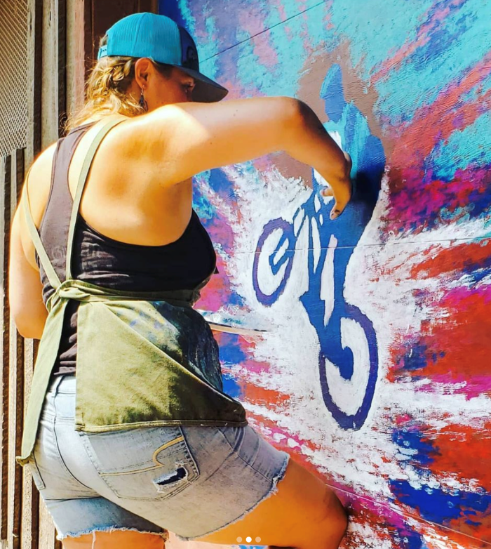 Author painting a mural of a mountain biker, with blue paint.
