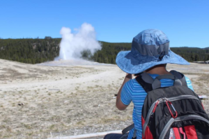 Child observing a thermal feature, steam rising from the ground, at Yellowstone National Park.