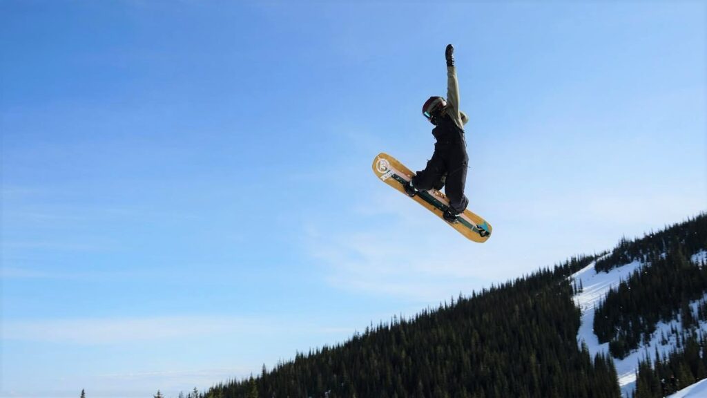 Maddie Hall flying through the air on her snowboard, doing a side grab, off a jump at Schweitzer's Stomping Ground Terrain Park.