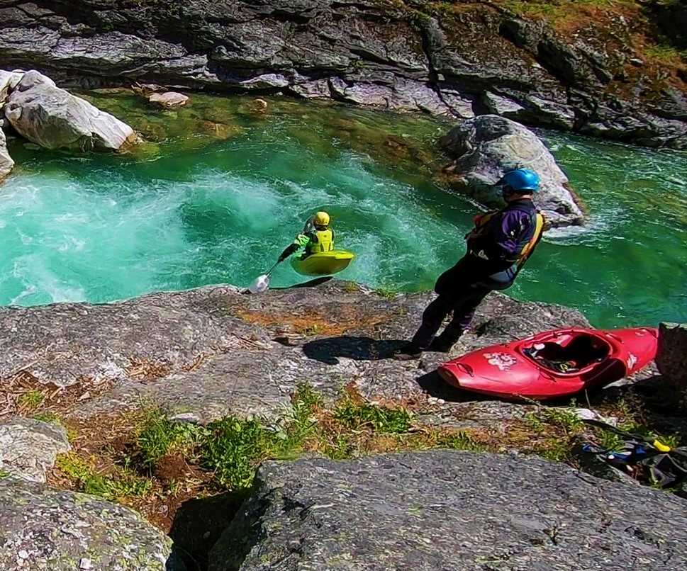 Kayaker taking short drop from a rock into whitewater river.