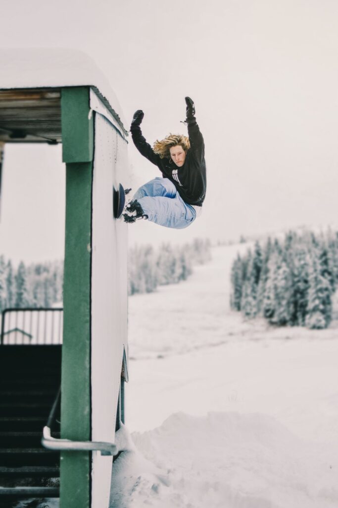 Austin Visintainer doing a snowboarding trick against the wall of the ski lodge.