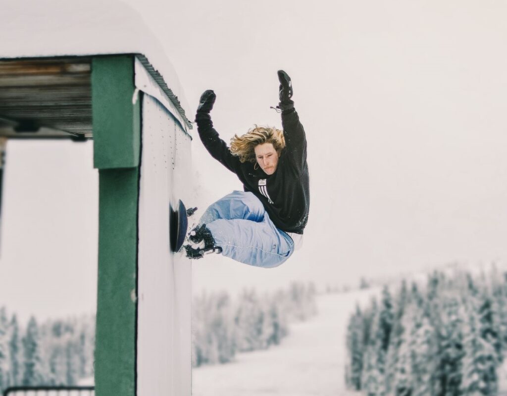 Austin Visintainer doing a snowboarding trick and riding along the ski lodge wall at Mt. Spokane Ski & Snowboard Park.