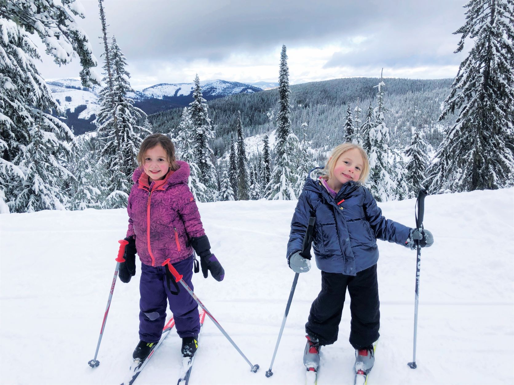 Two young girls smiling at the camera while cross-country skiing at Mt. Spokane.