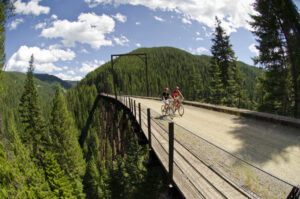 Two cyclists riding over one of the train trestles on the Route of the Hiawatha rail-trail.