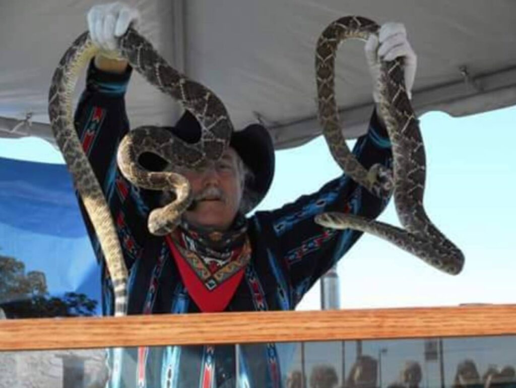 Guy holding up two snakes while giving a presentation at the Bighorn Show.