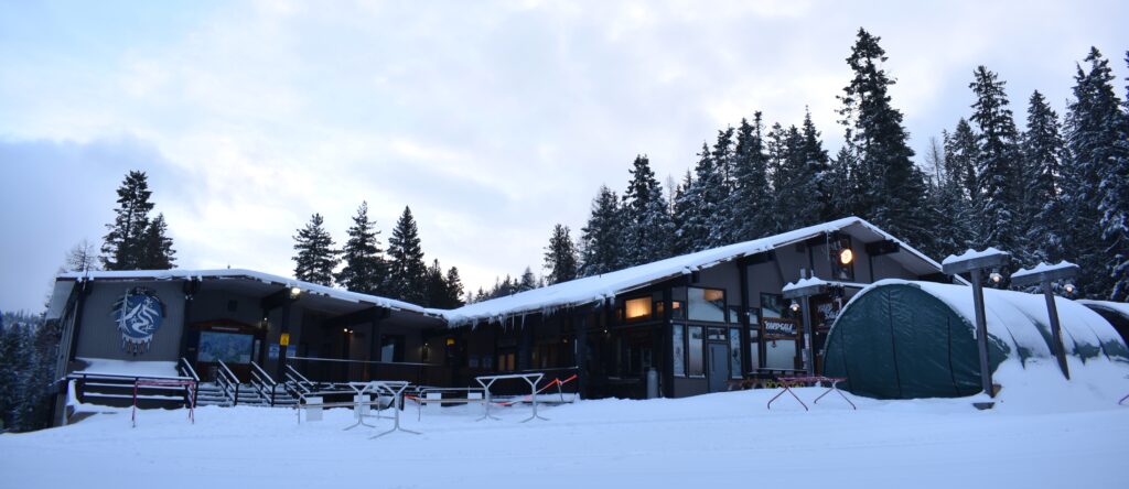 Lodge at 49 Degrees North - brown siding with deck and trees behind it.