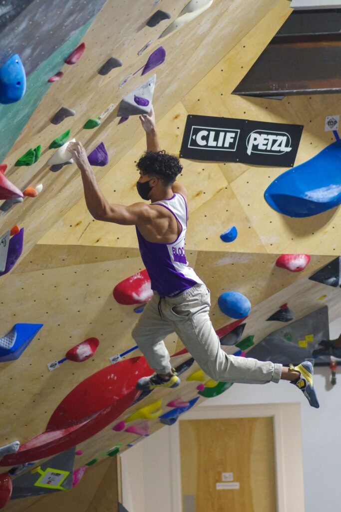 Ethan Anderson hanging from handholds while bouldering -- climbing without harness or ropes.