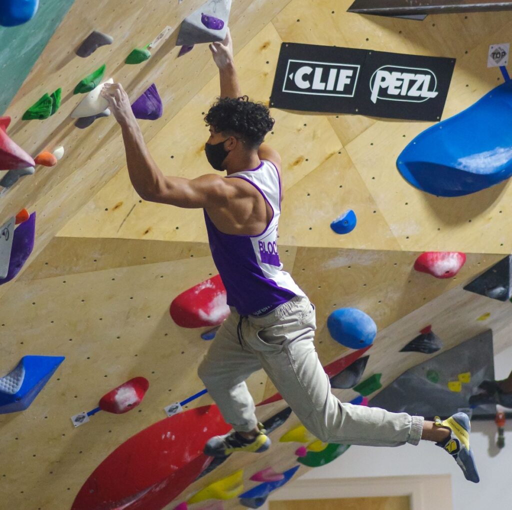 Ethan Anderson hanging from handholds while bouldering -- climbing without harness or ropes.