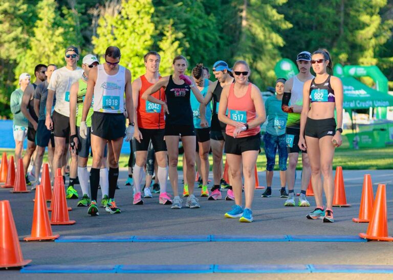 Group of runners of all genders at the start line for the Coeur d'Alene Marathon.