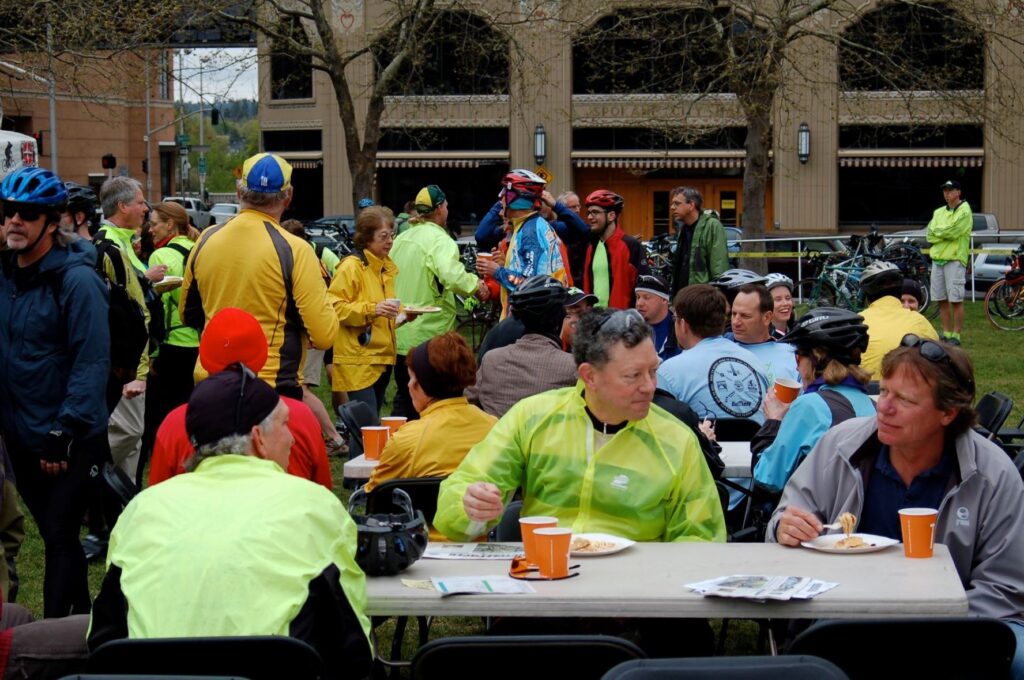 Bike commuters sitting at tables eating a pancake breakfast at Riverfront Park.