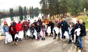 Volunteers holding empty garbage bags ready to participate in a litter clean-up event along the Spokane River.